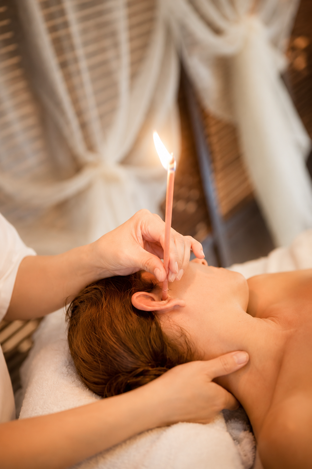 Ear candling treatment with a lit ear candle